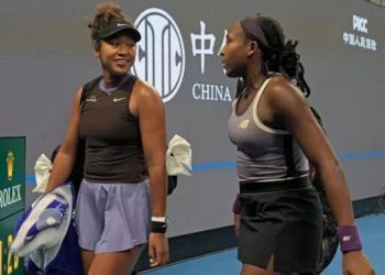 Coco Gauff assists an injured Naomi Osaka in walking off the court after she is forced to forfeit the game due to back problems.
